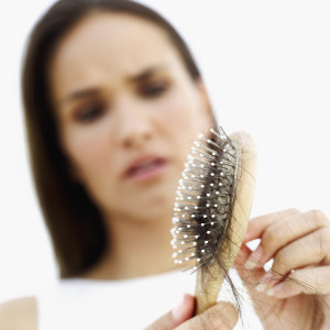 close-up of a young woman removing hair from a hairbrush